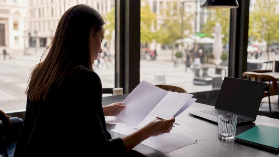 Iemand bladert met de handen door stapels sollicitatiemapjes op het bureau.